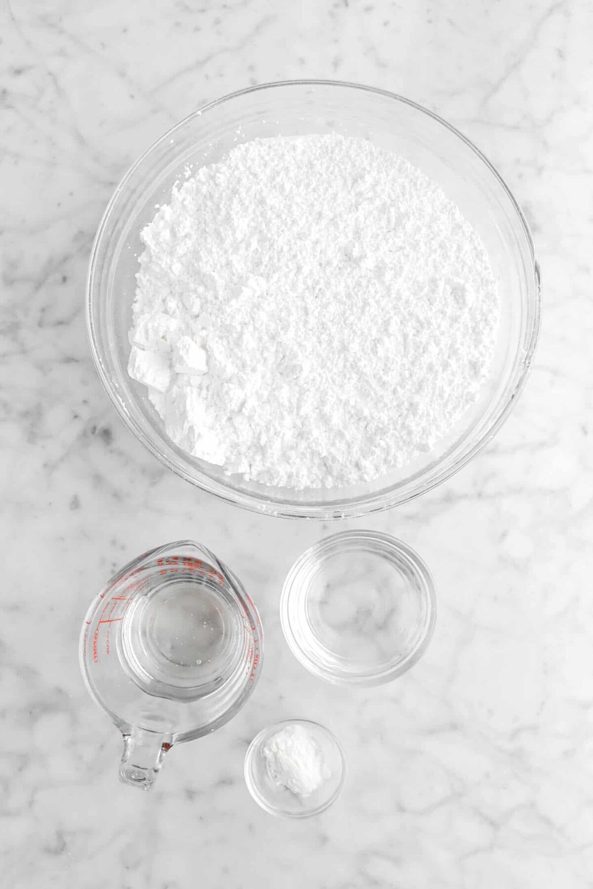 powdered sugar, corn syrup, water, and vanilla powder on marble counter