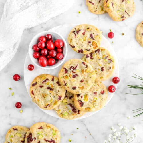cookies on round marble plate with bowl of cranberries and more cookies around