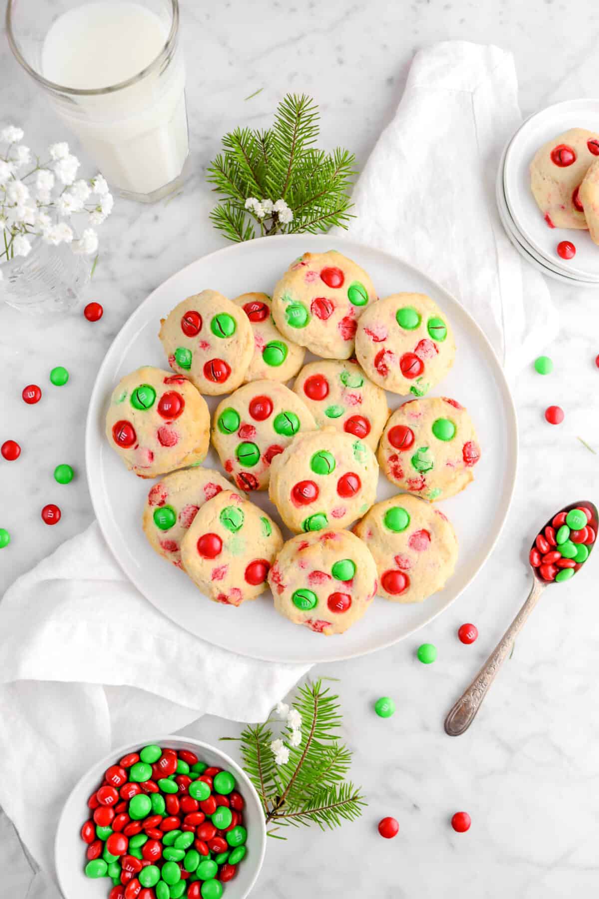 cookies on white plate with glass of milk, m&m's, and greenery