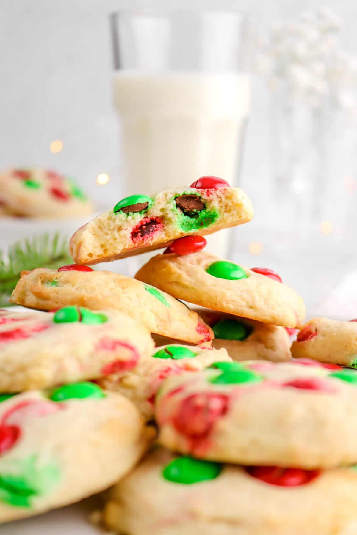 cookies piled with one missing a bite with glass of milk behind