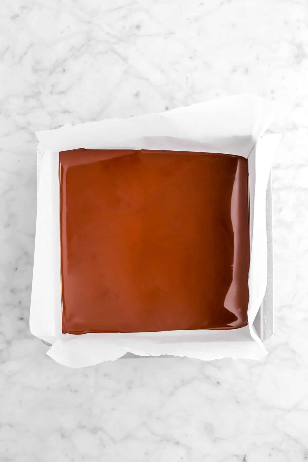 melted chocolate in lined square cake pan