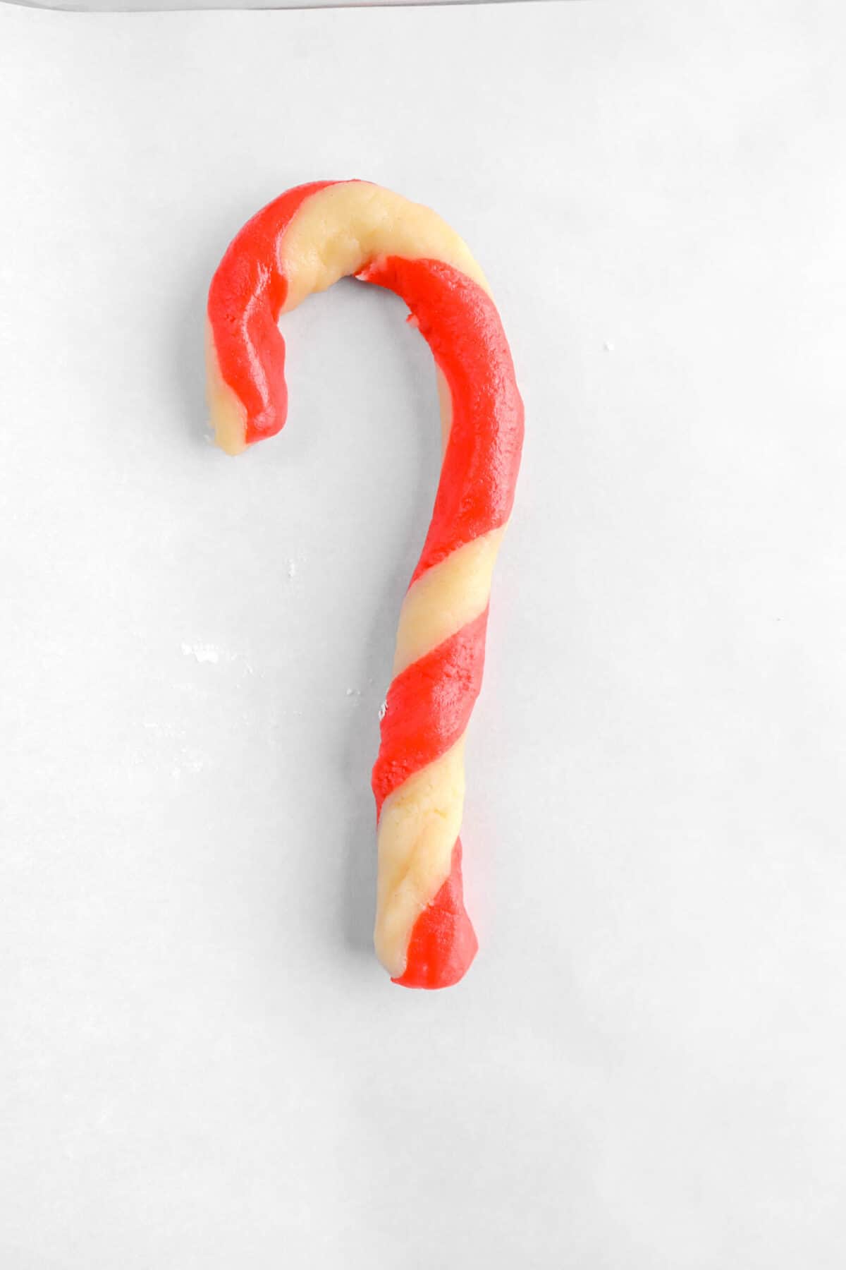 candy cane shaped cookie dough on parchment paper
