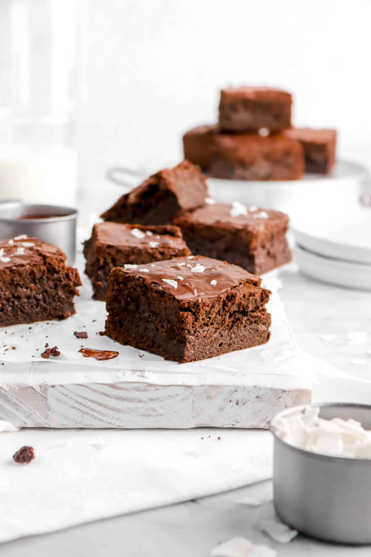 five brownies on white board with small bowl of coconut flakes