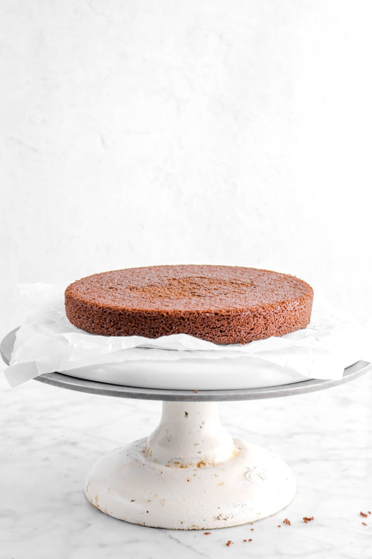 chocolate cake layer on parchment paper on a cake stand