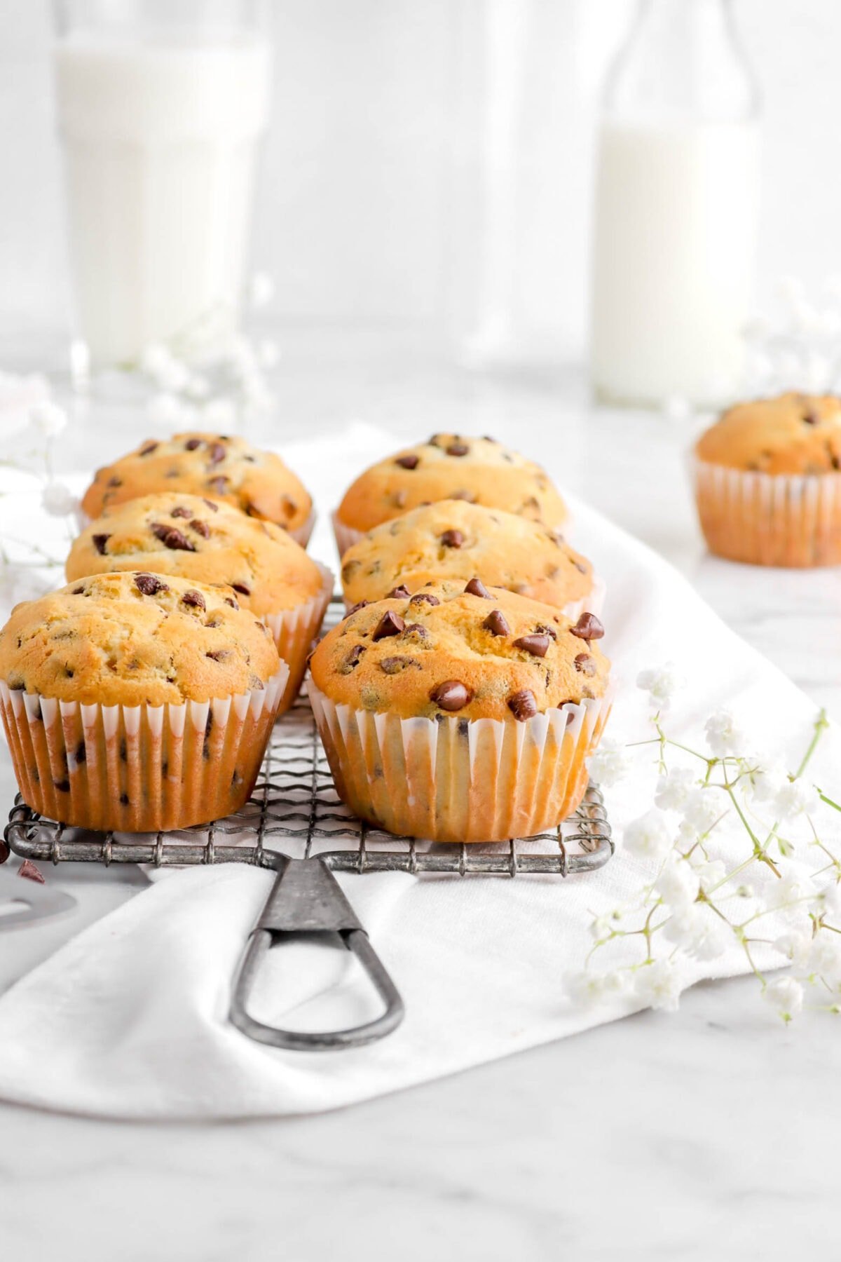 chocolate chip muffins on cooling rack with white napkin and flowers