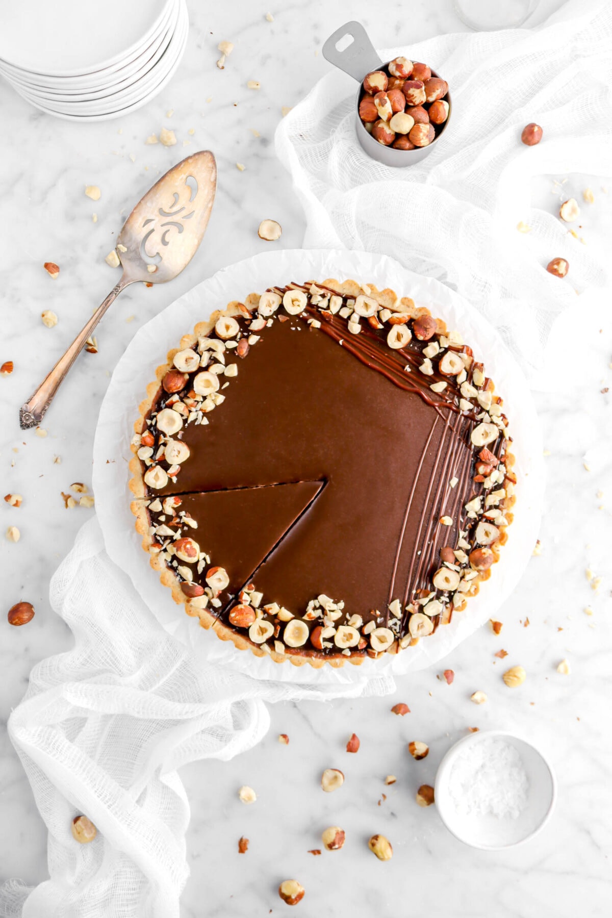 chocolate hazelnut tart cut on white plate with parchment paper on a white cheese cloth