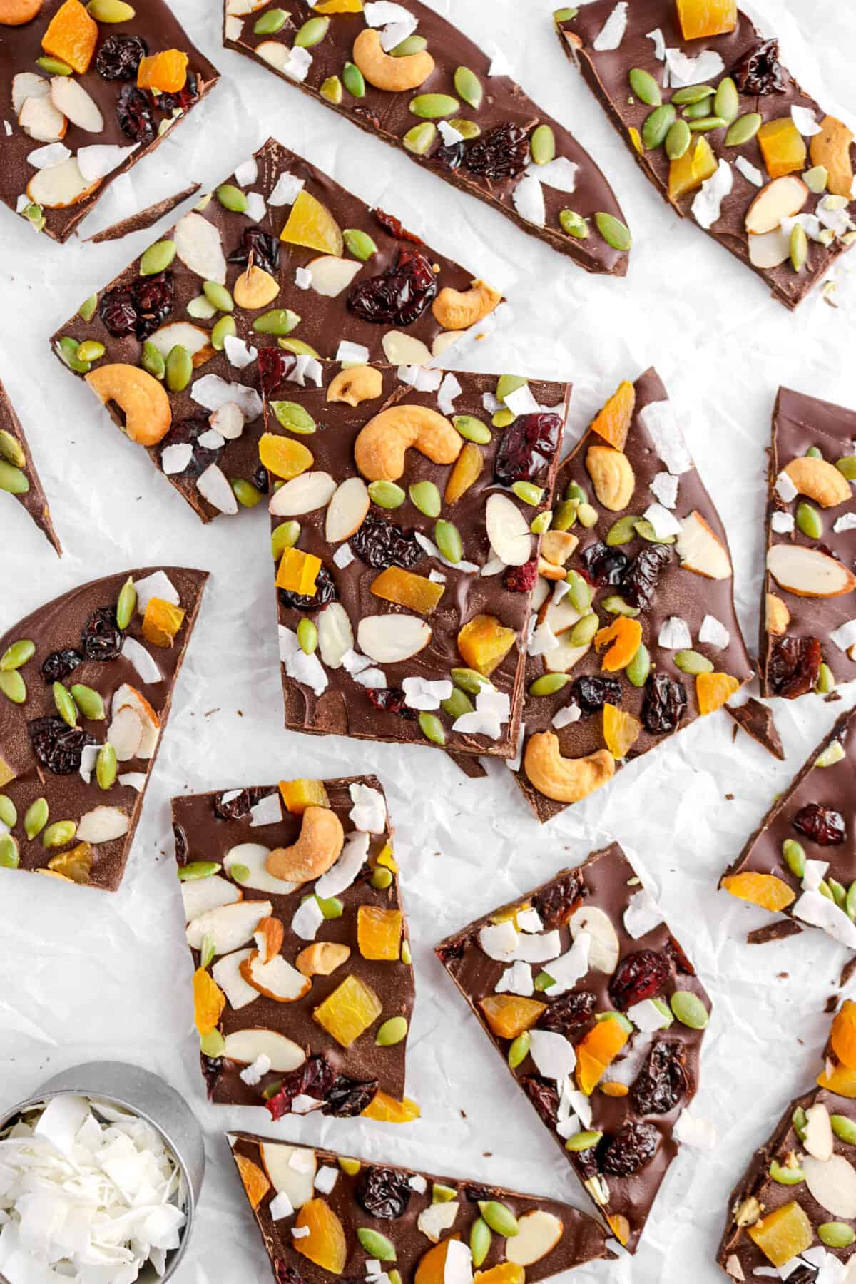 chocolate bark on parchment paper with bowl of coconut flakes