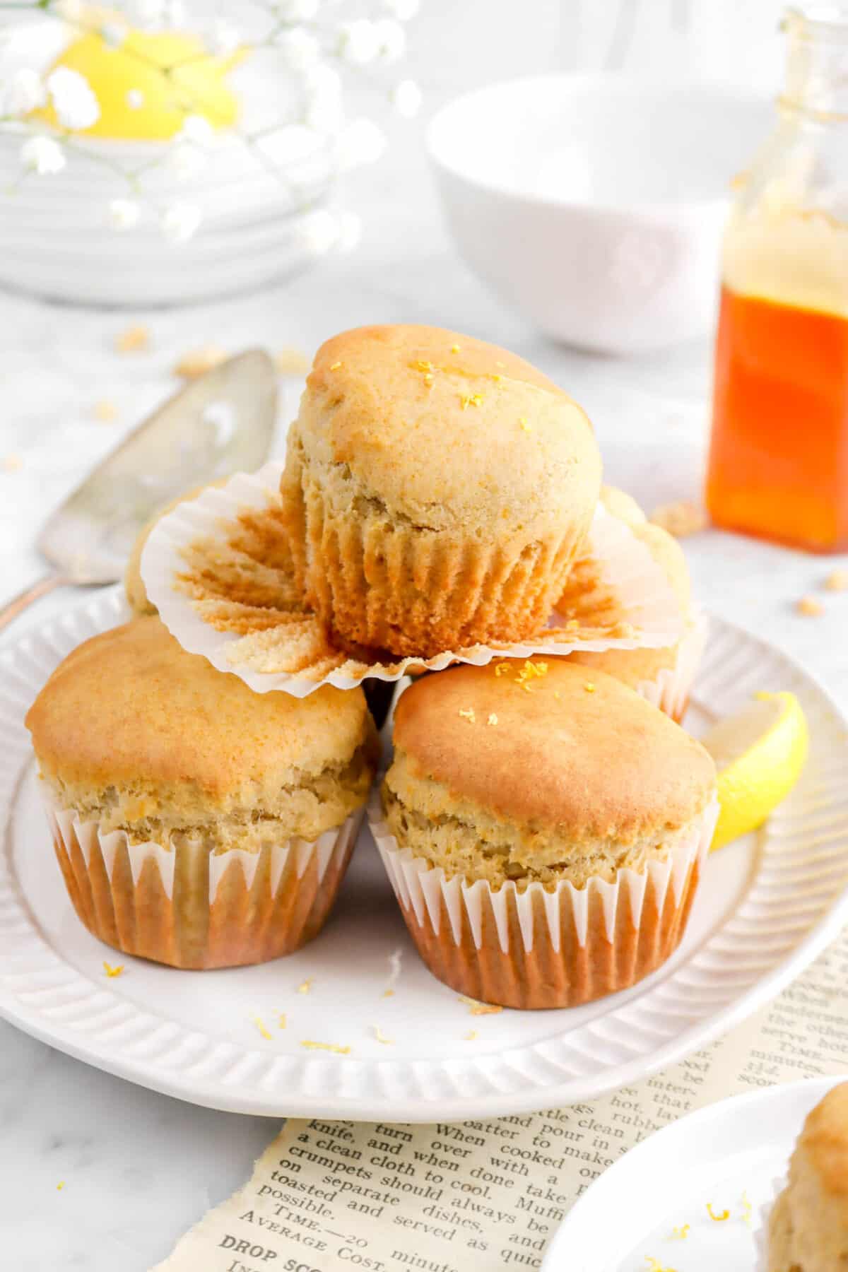 overhead angled shot of five muffins stacked on white plate with paper pulled off top mufin