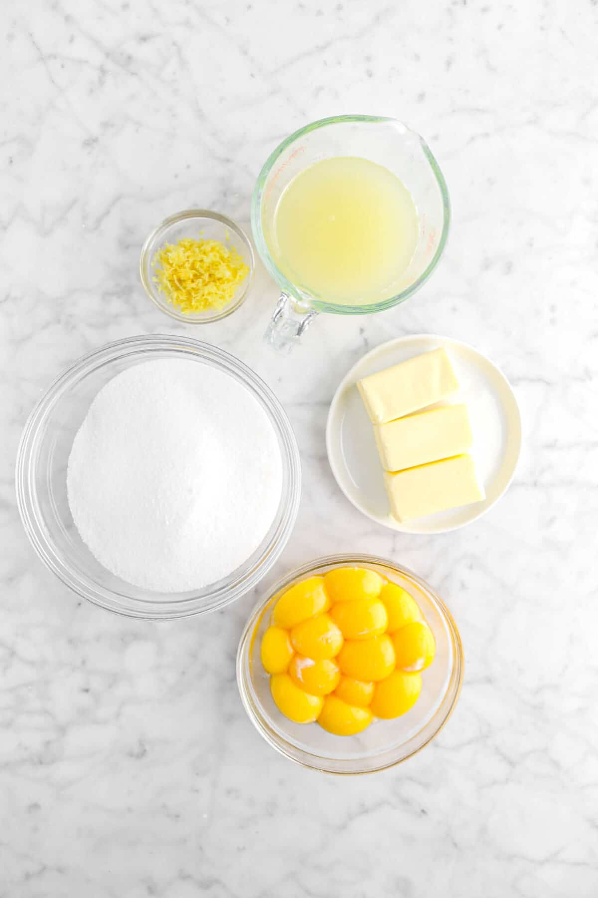lemon zest, lemon juice, sugar, butter, and egg yolks on marble surface