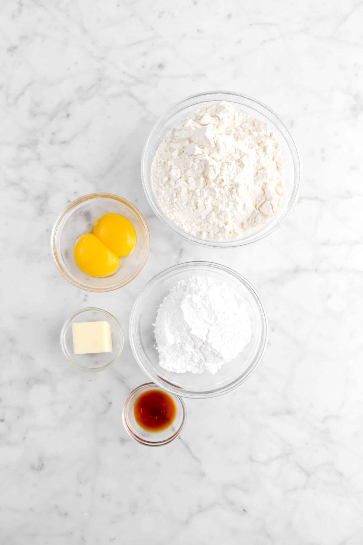 flour, egg yolks, powdered sugar, butter, and vanilla on marble counter