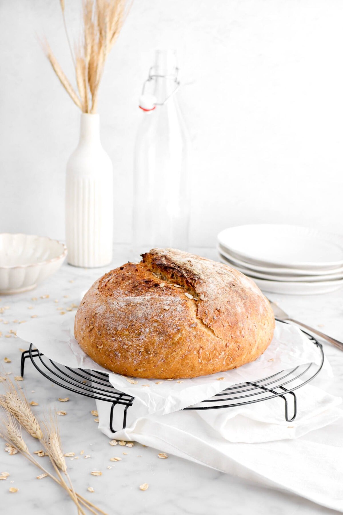 multigrain bread on wire cooling rack with white napkin and wheat stems behind