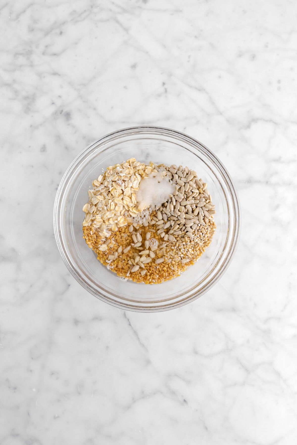 oats, salt, flaxseeds, sunflower seeds, and water in glass bowl