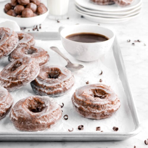 doughnuts on sheet pan wit cup of coffee behind