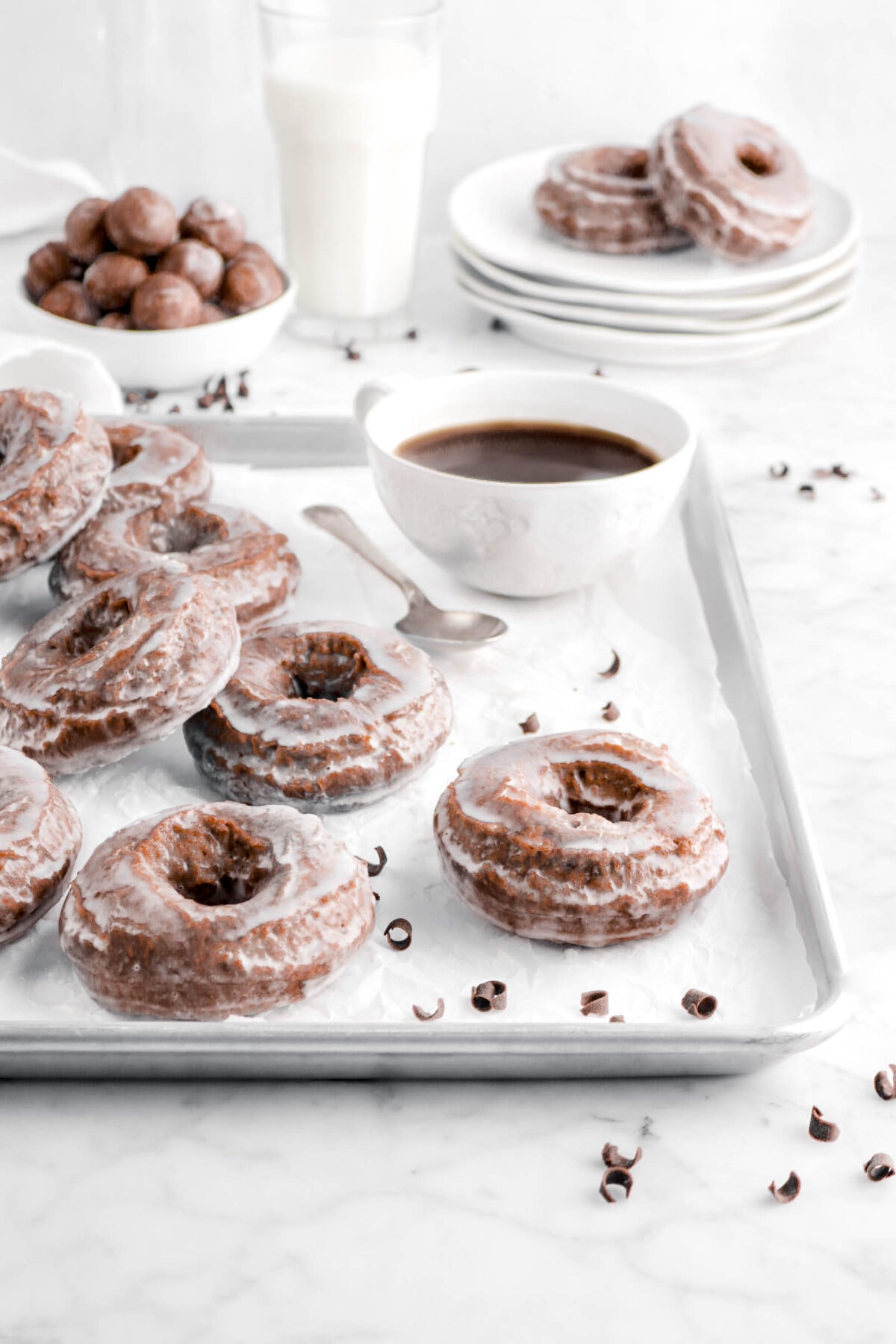 doughnuts on sheet pan wit cup of coffee behind