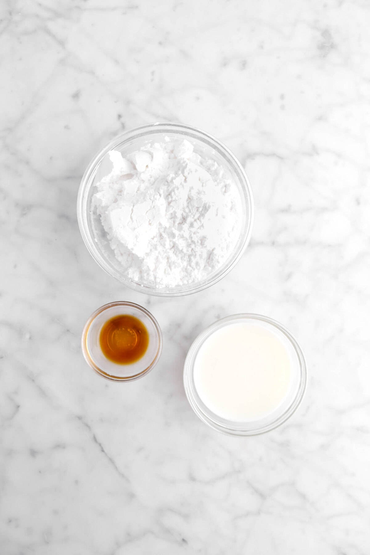 powdered sugar, vanilla, and milk on marble surface