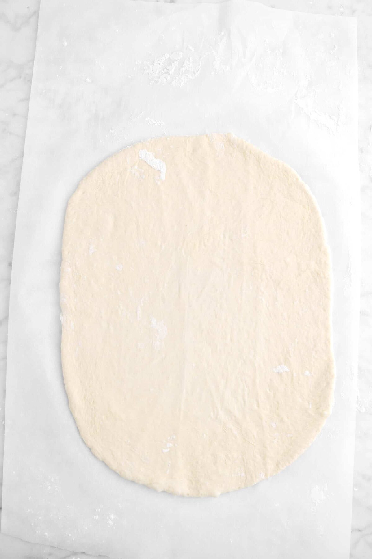 rolled out pizza dough on parchment paper