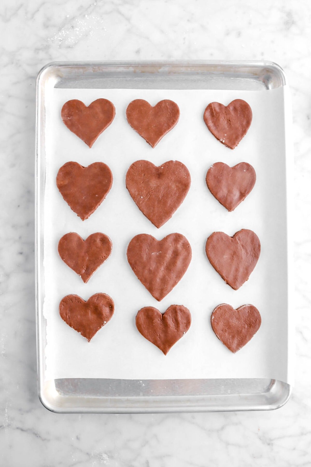 heart shaped chocolate cookie dough on lined baking sheet