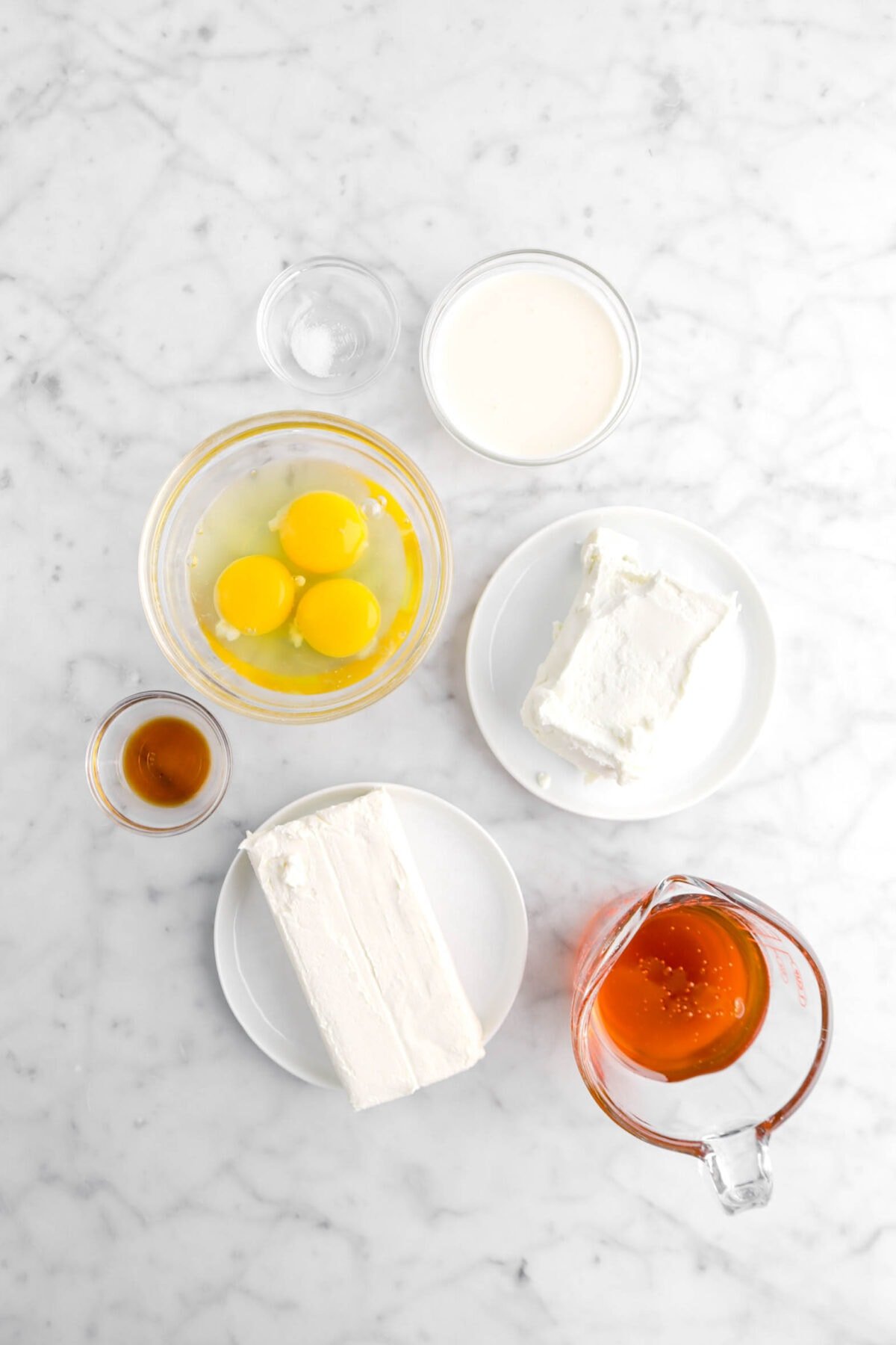 salt, heavy cream, eggs, goat cheese, cream cheese, vanilla, and honey on marble counter