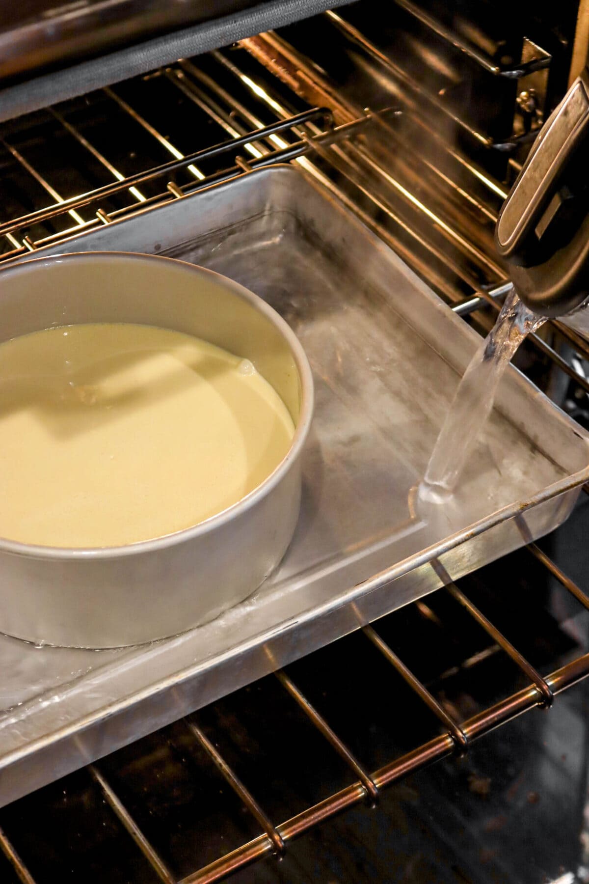 hot water being poured into large cake pan with cheesecake in the middle