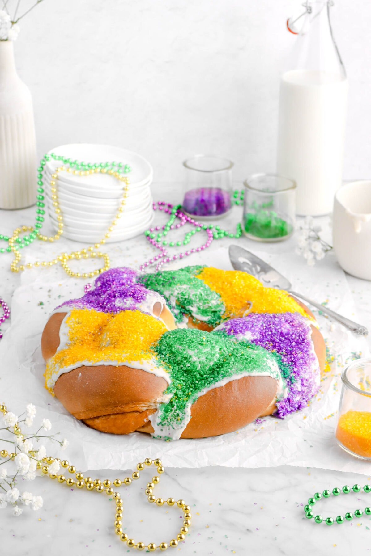 king cake on parchment paper with mardi gras beads around