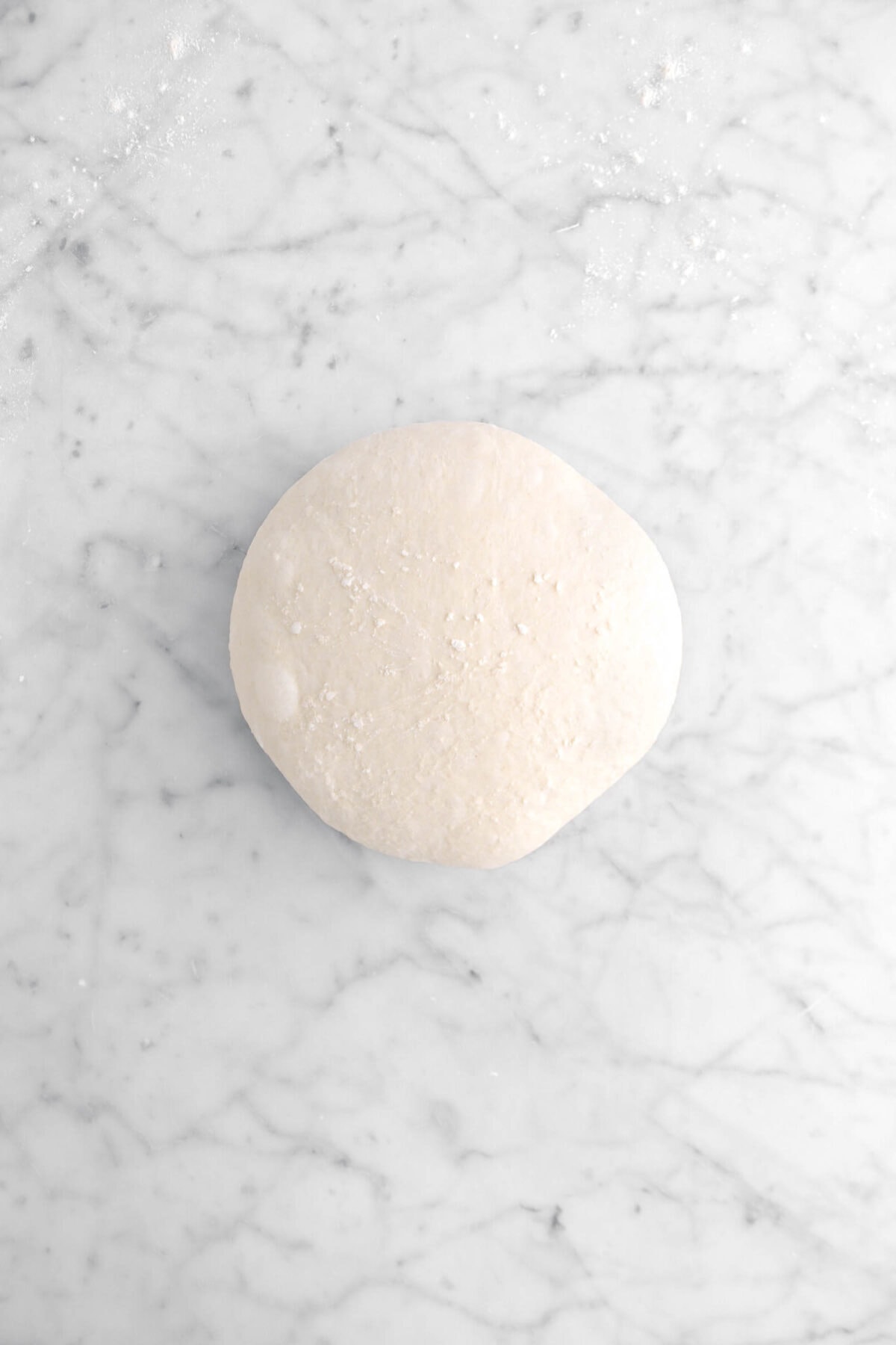 smooth dough boule on marble surface