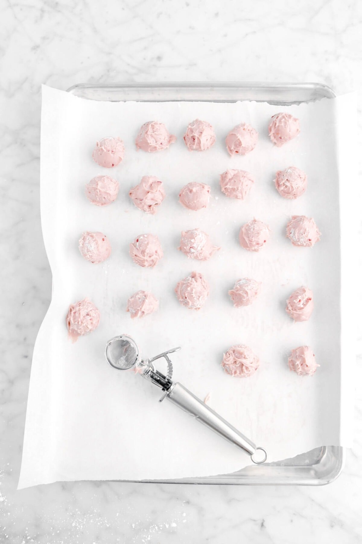 raspberry ganache scooped into balls on lined sheet pan
