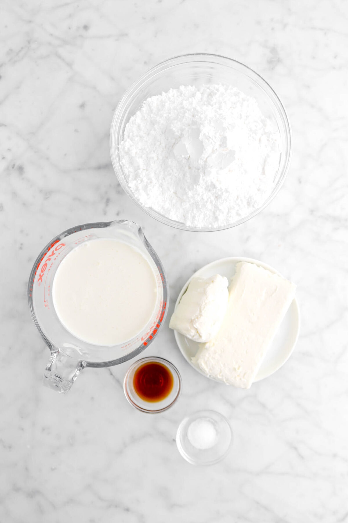 powdered sugar, heavy cream, cream cheese, vanilla extract, and salt on marble surface