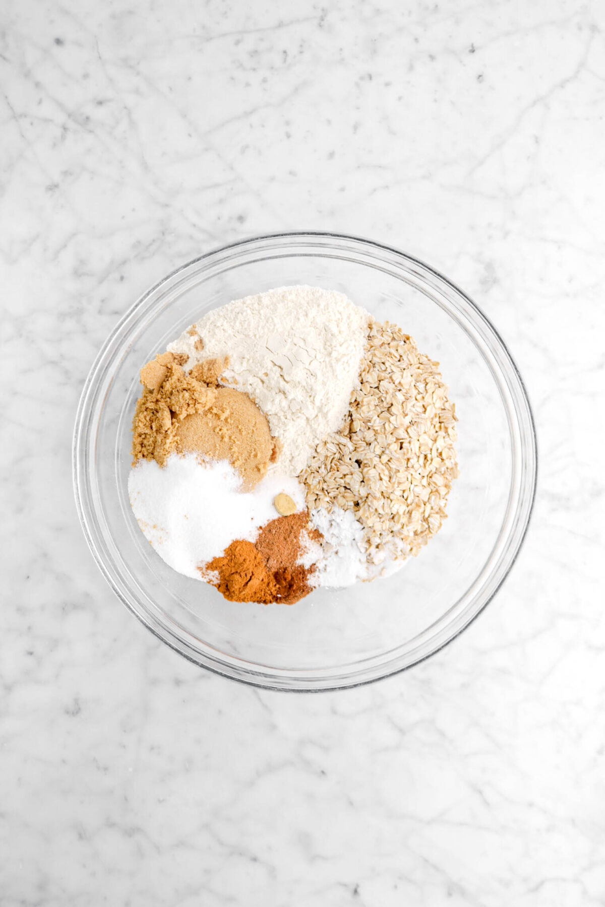 flour, brown sugar, granulated sugar, spices, and oatmeal in glass bowl