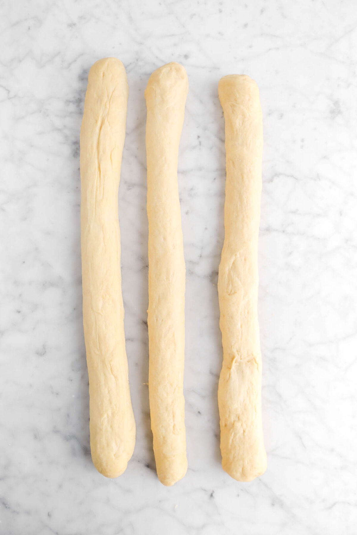 three long strands of dough on marble surface
