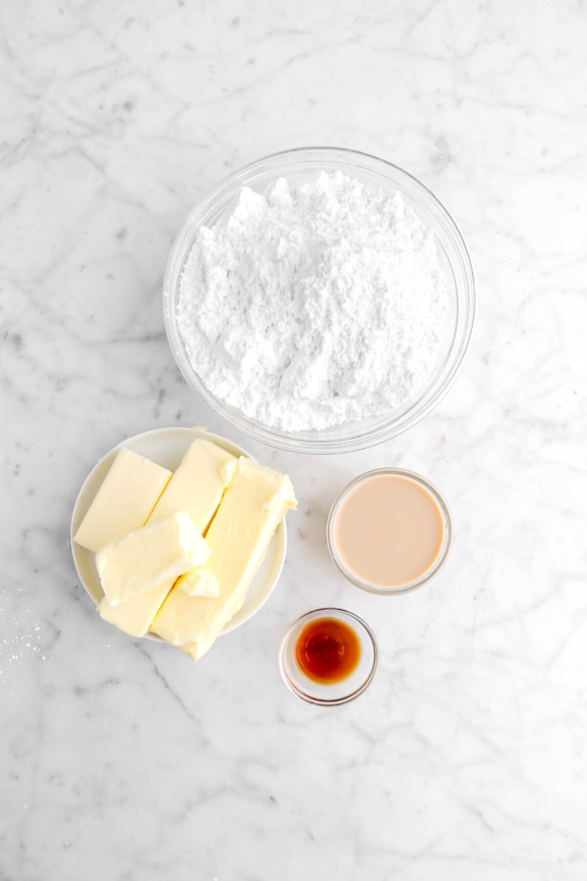 powdered sugar, butter, irish cream, and vanilla on marble surface