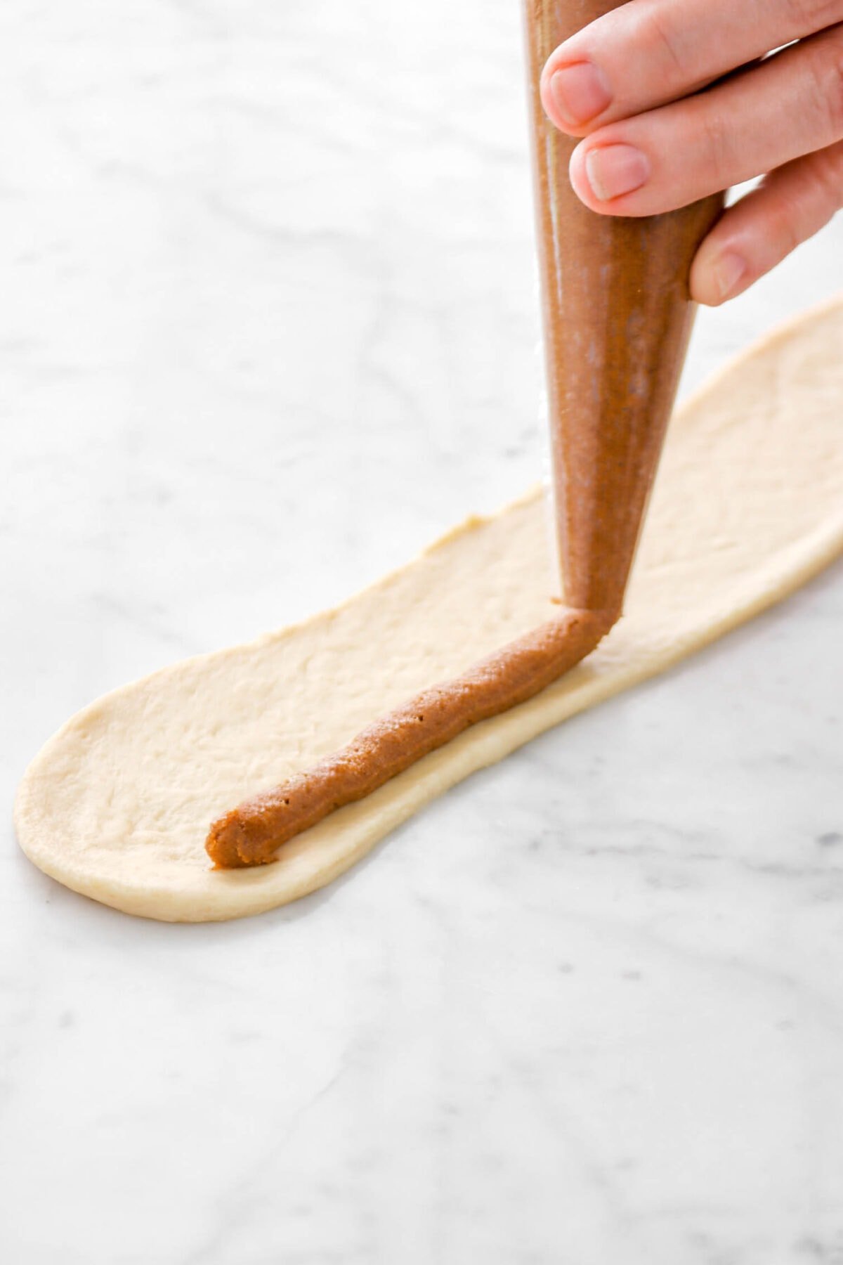 cinnamon sugar schmear being piped onto rolled out dough