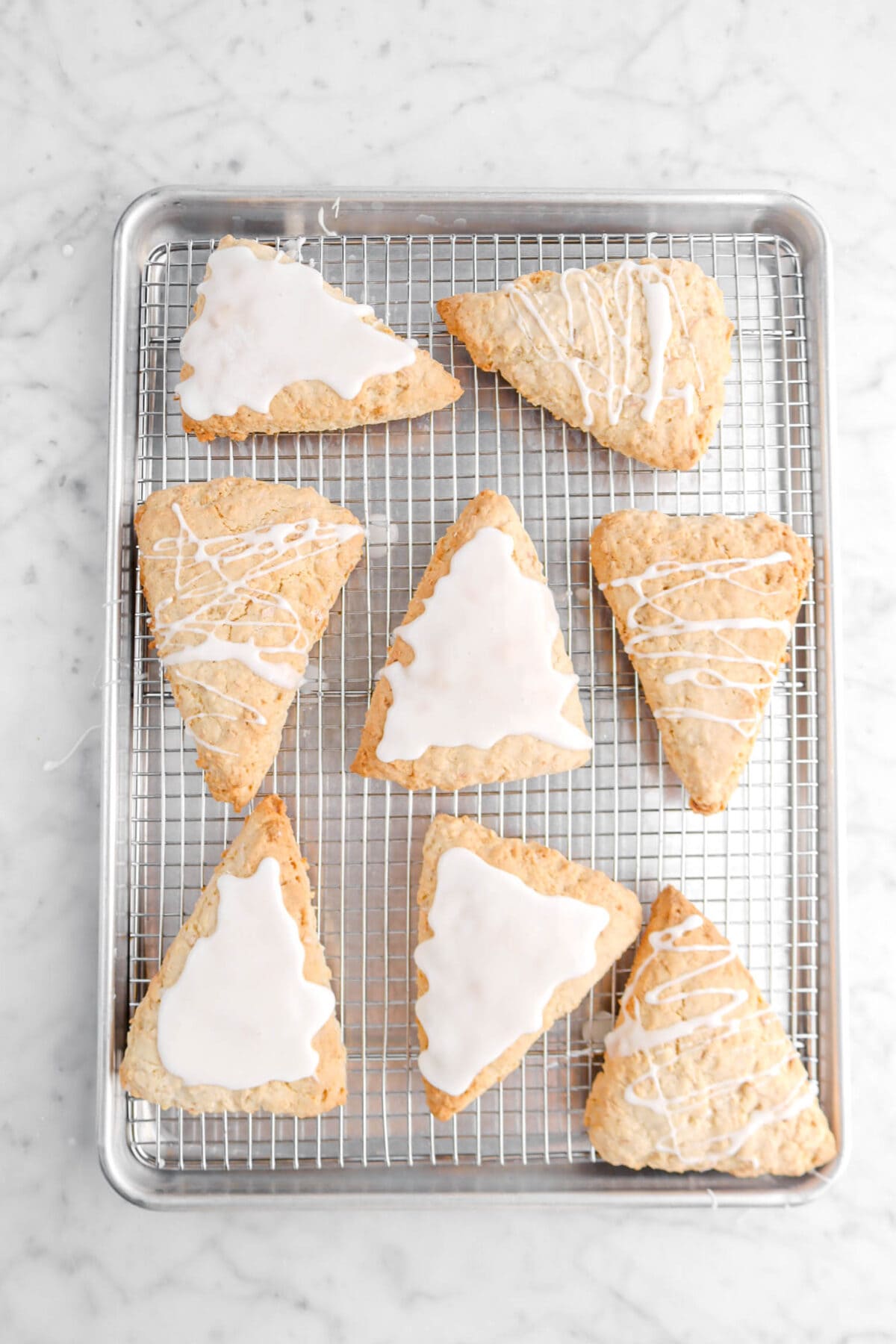 eight scones decorated with icing on wire rack lined sheet pan