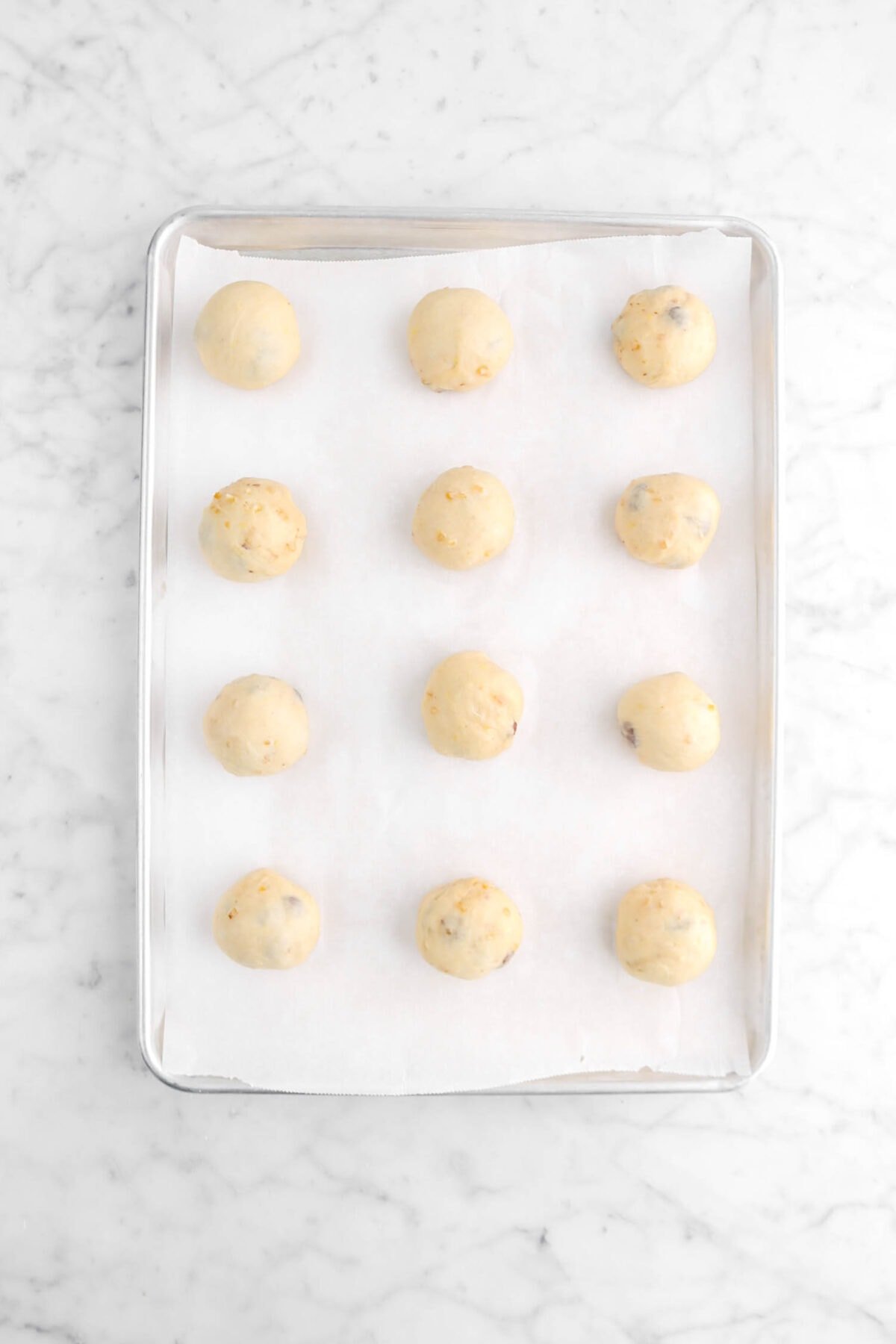 twelve dough balls on parchment lined sheet pan