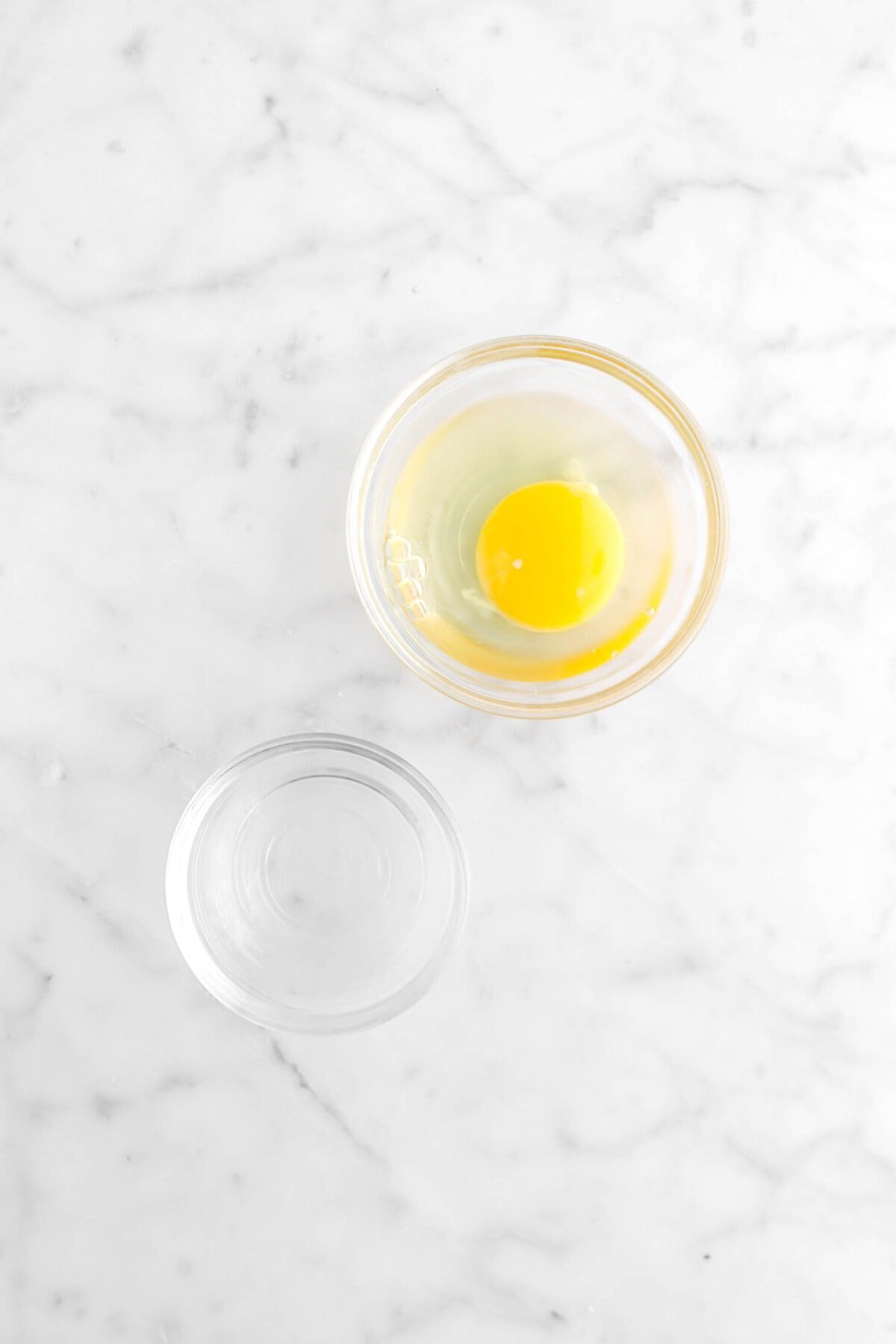 bowl of egg and bowl of water on marble counter