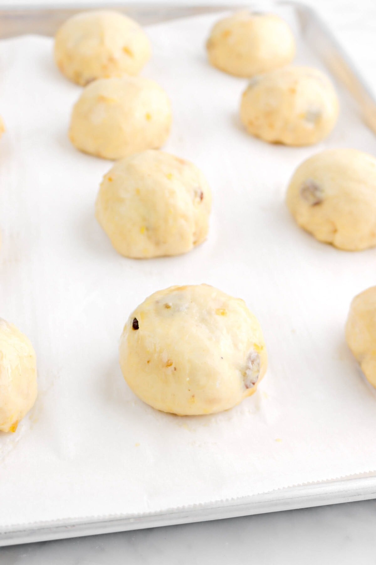 angled photo of dough balls balls on parchment lined pan