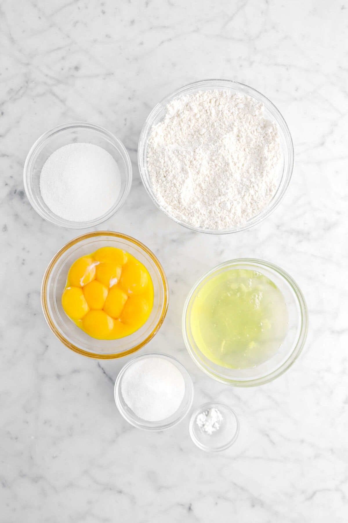 sugar. flour, egg yolks, egg whites, sugar, and cream of tartar on marble surface