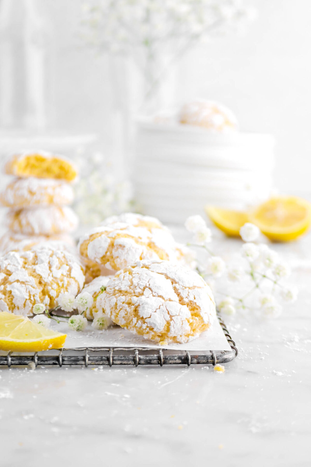 crinkle cookies on small wire tray with parchment paper, flowers, and lemon slices