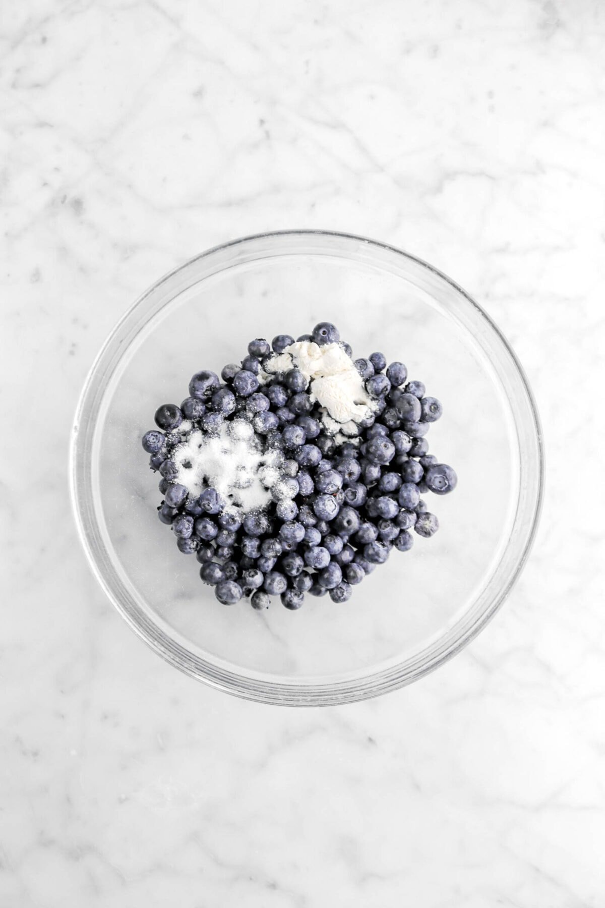 blueberries, sugar, and flour in glass bowl