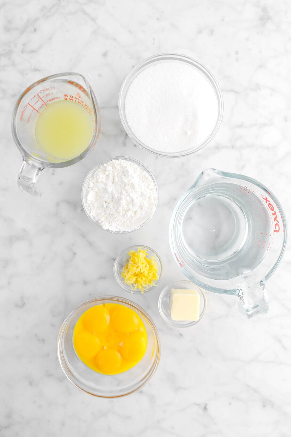 lemon juice, sugar, corn starch, water, lemon zest, butter, and egg yolks on marble surface