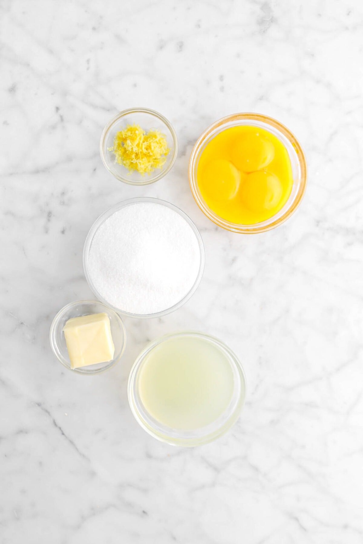 lemon zest, egg yolks, sugar, butter, and lemon juice on marble surface