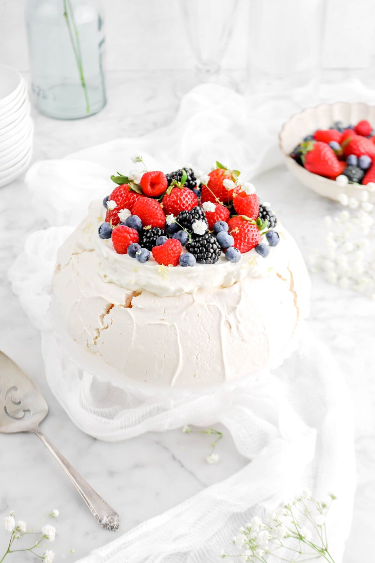 angled cloth up of pavlova with whipped cream and mixed berries on top