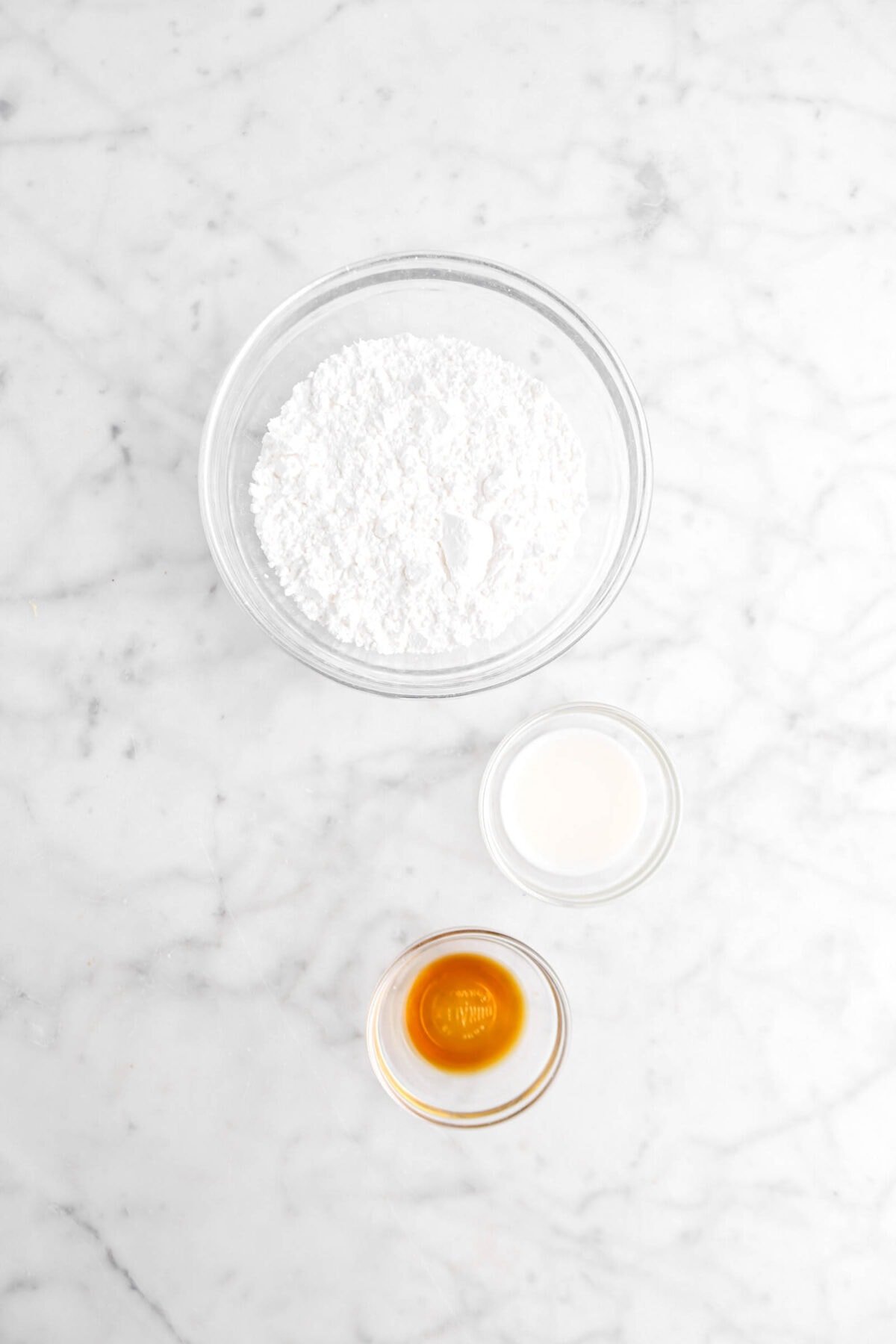 powdered sugar, milk, and vanilla on marble surface