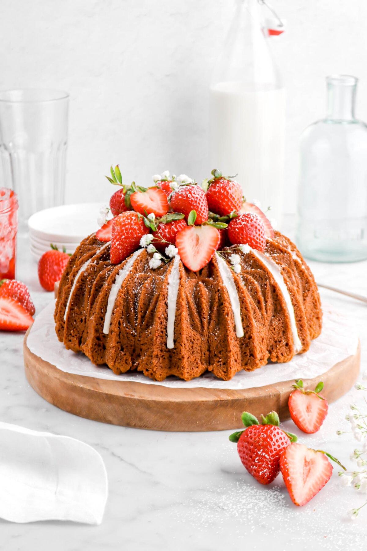 bundt cake on wood board with strawberries and flowers on top