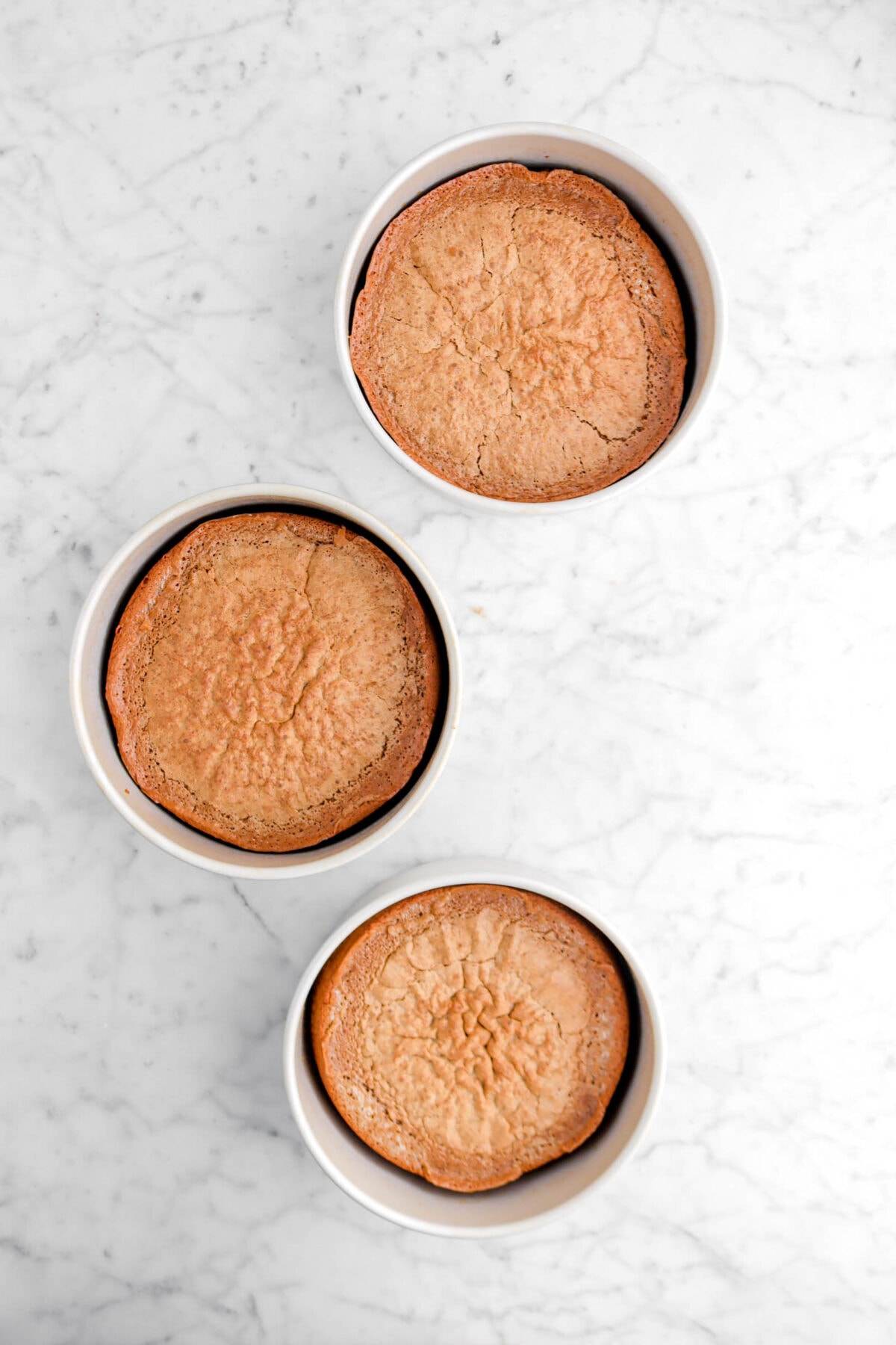 three baked chiffon cakes in round pans on marble surface
