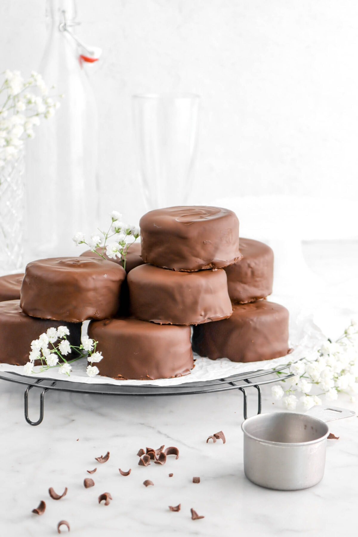 stacked chocolate coated cakes on wire cooling rack with flowers