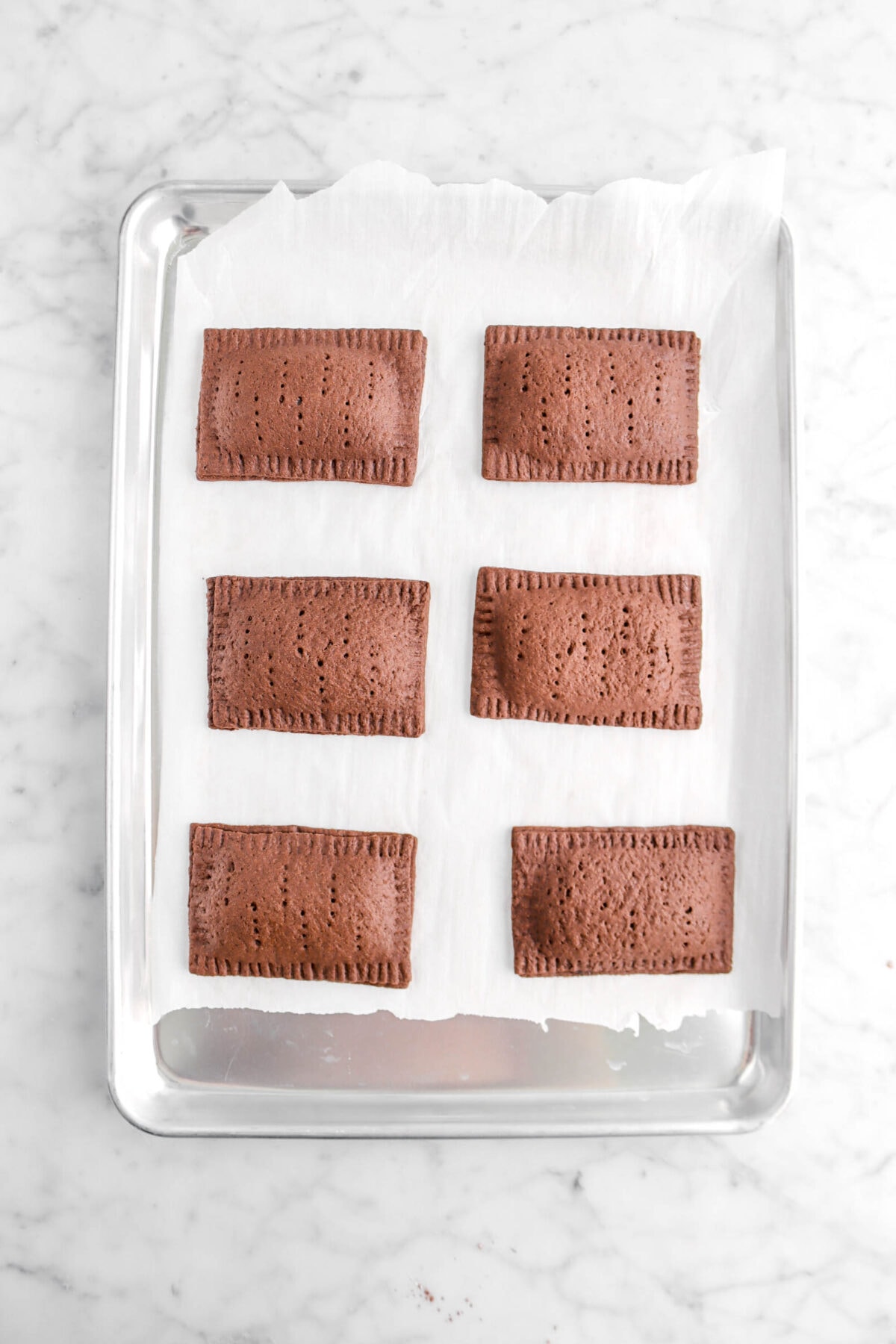 six baked chocolate pastries on lined sheet pan