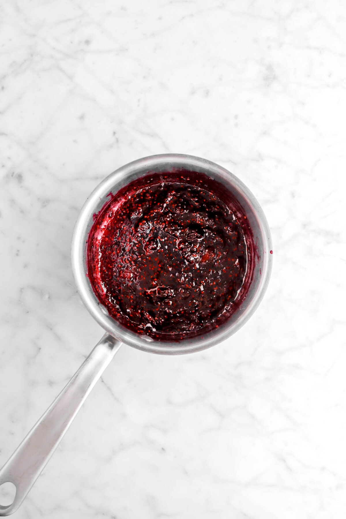 blackberry jam in small saucepan on marble surface