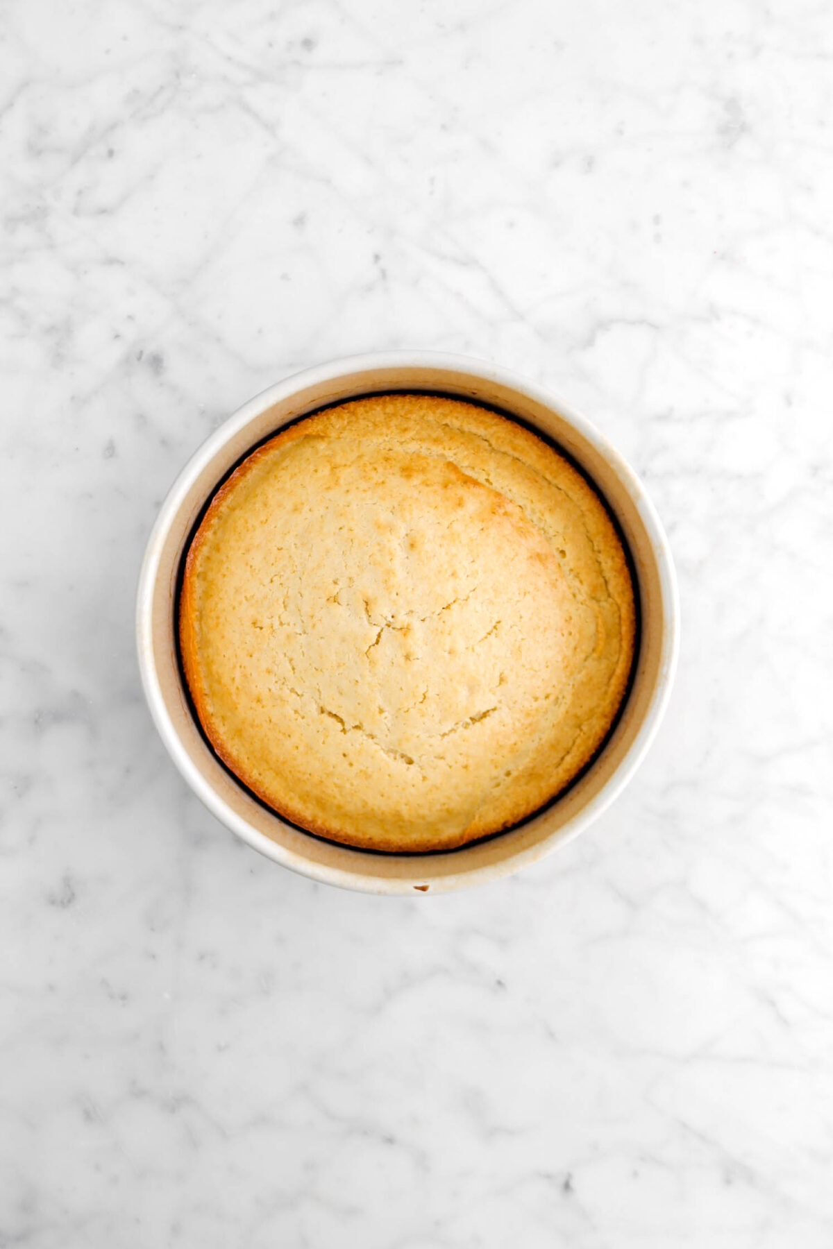 baked cake in round cake pan on marble surface