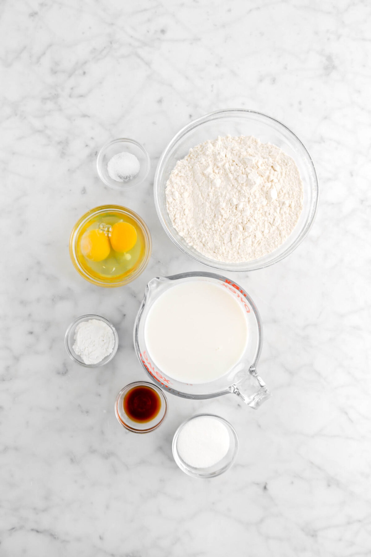 salt, flour, eggs, milk, baking powder, vanilla, and sugar in marble surface