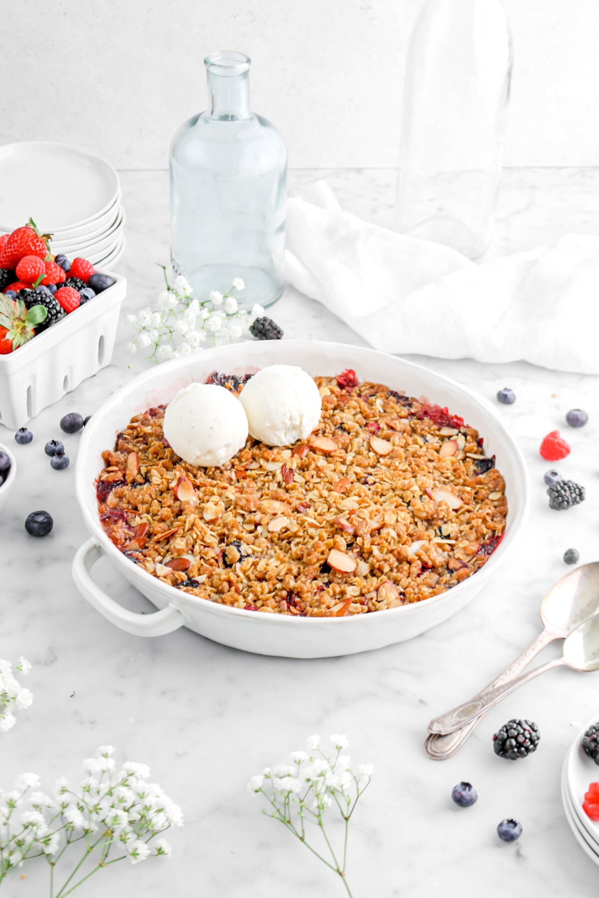 angled shot of mixed berry crisp with two scoops of ice cream on marble surface